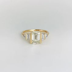 a yellow gold ring with three baguettes on the side and two diamonds in the middle