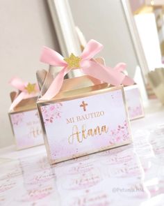 two small boxes with pink bows on them sitting on a table in front of a mirror