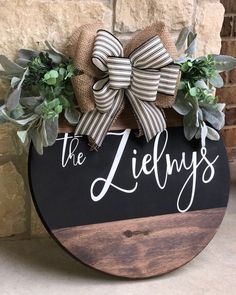 a wooden sign that says the jennys on it with greenery in front of a brick wall