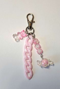 a pink and white keychain with charms attached to it's side on a white surface