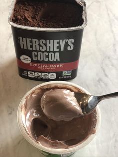 a bowl of ice cream next to a cup of chocolate pudding with a spoon in it