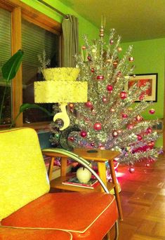 a christmas tree in the corner of a living room with red and green ornaments on it