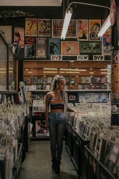 a woman is walking down the aisle of a record store with many cds on display