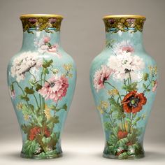 two vases with flowers painted on them sitting side by side in front of each other