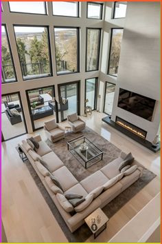 a large living room with high ceilings and floor to ceiling windows overlooking the surrounding area