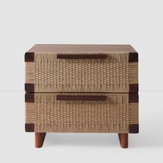 a wicker and wood side table with two drawers on each side, one drawer open