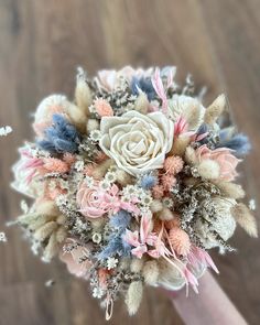 a bridal bouquet with pink, blue and white flowers in it on a wooden floor