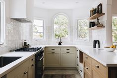 a kitchen with white counter tops and wooden cabinetry next to a window that looks out onto the trees