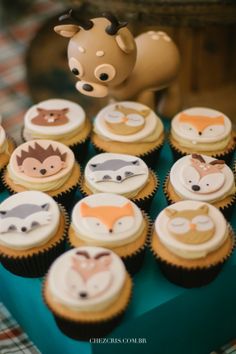 cupcakes with animals on them are sitting on a blue tray next to a toy horse