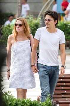 a young man and woman walking down the street holding hands with each other while wearing sunglasses