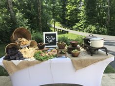 a table topped with lots of food next to a forest