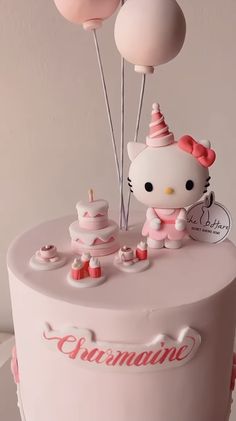 a hello kitty birthday cake with balloons on top