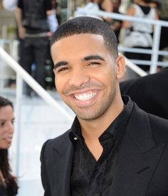 a man smiling and standing in front of some stairs with other people behind him onlookers