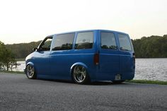 a blue van parked on the side of a road next to a body of water