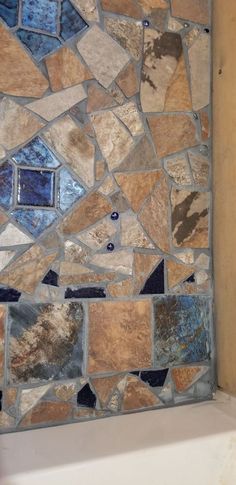 a bath tub sitting next to a stone wall in a bathroom with tile on the walls