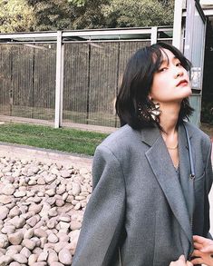 a woman standing in front of a fence with her hand on her hip looking up