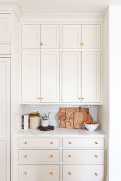 a kitchen with white cabinets and gold handles