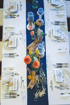 the table is set with silverware, plates and flowers in vases on it