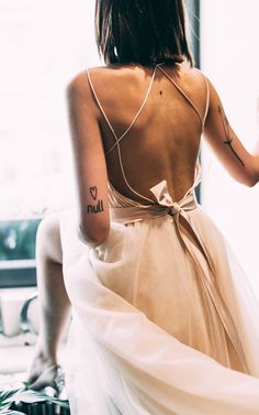 the back of a woman's dress with tattoos on her arm