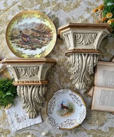 three plates and two vases sitting on top of a table with an open book