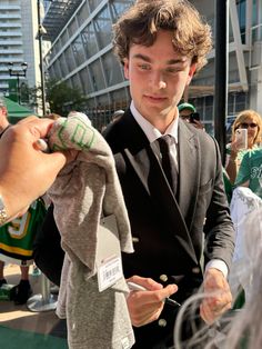 a young man in a suit and tie is holding an item with his right hand