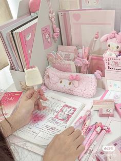 a woman is writing in a notebook surrounded by hello kitty items