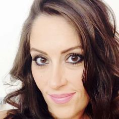 a close up of a woman with long hair and blue eyes smiling at the camera