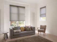 a living room filled with furniture and windows covered in shades on the window sill