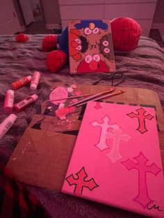 art supplies are laid out on a bed with pink sheets and crayon markers