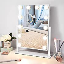 a white vanity mirror sitting on top of a desk next to a vase with flowers