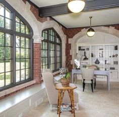 a living room filled with furniture and windows next to a dining room table covered in chairs