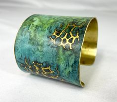 These unique, hand-formed copper and brass cuff bracelets with vibrant patinas create stunning accents to your personal style. Dress up or down- either way you'll be wearing an adornment that will turn heads, start conversations, and delight the eye of the beholder. This is a hammered cuff with bright brass peeking through a vivid marbled green/blue patina. Please note that patina colors will look different depending on the screen/device you view them on. This is a small cuff- see measurements b Luxury Traditional Metal Cuff Bracelet, Adjustable Green Cuff Bracelet, Brass Cuff Bracelet With Patina As A Gift, Unique Hammered Brass Cuff Bracelet, Unique Metal Cuff Bracelet With Hammered Detail, Unique Brass Cuff Bracelet, Artistic Adjustable Patina Cuff Bracelet, Unique Patina Cuff Bangle Bracelet, Adjustable Patina Cuff Bracelet