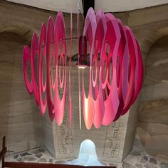 a pink light fixture hanging from the ceiling in a room with stone walls and flooring