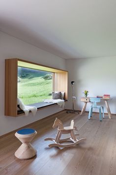 a child's room with wooden furniture and large window overlooking a green field in the distance