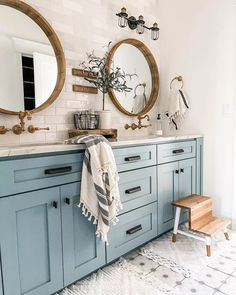 a bathroom with two round mirrors and blue cabinets