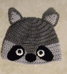 a crocheted raccoon hat on the floor