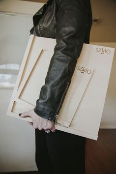 a person holding two pieces of cardboard in their hands and wearing a black leather jacket