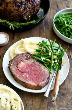 a plate with meat, mashed potatoes and green beans next to a roasting pan