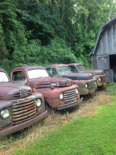 several old trucks parked in front of a barn