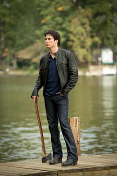 a man standing on a dock with a shovel in his hand and looking off into the distance