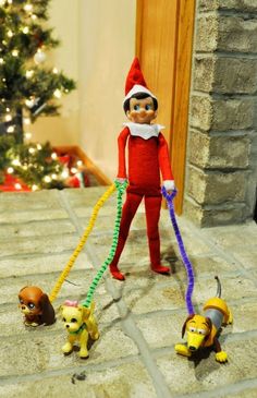 an elf is walking three small dogs in front of a christmas tree