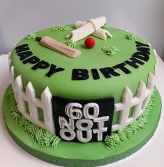 a green birthday cake with white fence and red ball on top that says happy birthday go not out