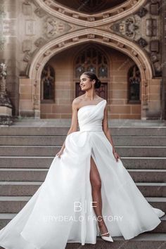 a woman standing on some steps wearing a white dress with one leg slited in the air