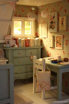 a doll house room with furniture and pictures hanging on the wall, including a dresser