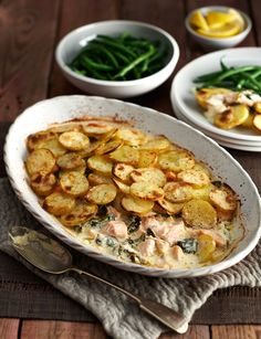 a casserole dish with potatoes, green beans and other vegetables on the side