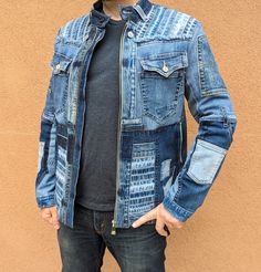 a man standing in front of a wall wearing a jean jacket