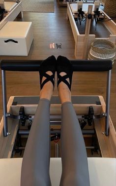 the legs of a woman who is sitting on a machine in a room with tables and chairs