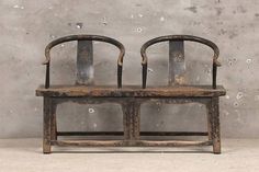 two wooden chairs sitting next to each other in front of a concrete wall with water droplets on it