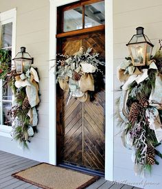 two christmas wreaths on the front door of a house with pine cones and other holiday decorations