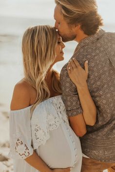 a man and woman are kissing on the beach while holding each other's hands